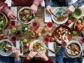 Directly above view of unrecognizable friends eating together at diner party